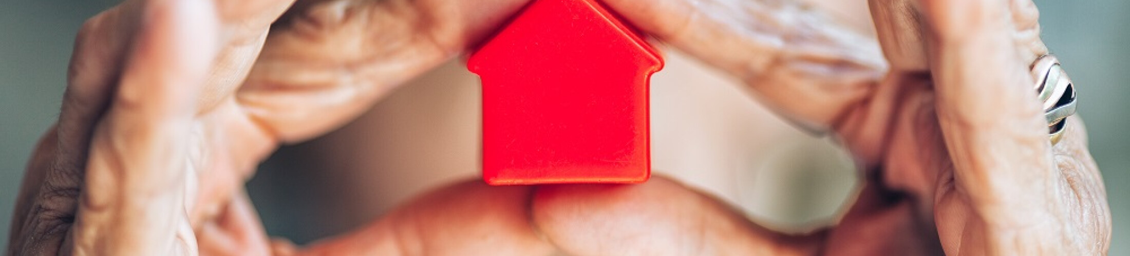 Femme senior qui tient une maison miniature dans ses mains