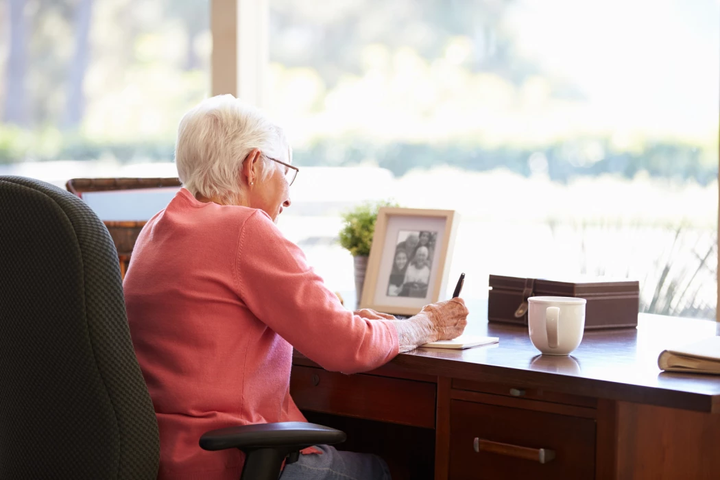 Femme senior qui écrit à son bureau